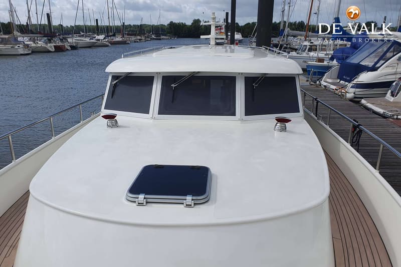 De foto toont de boeg van een witte motorboot met een luik en ramen, liggend in een jachthaven. — Brandsma Noordzeekotter 38