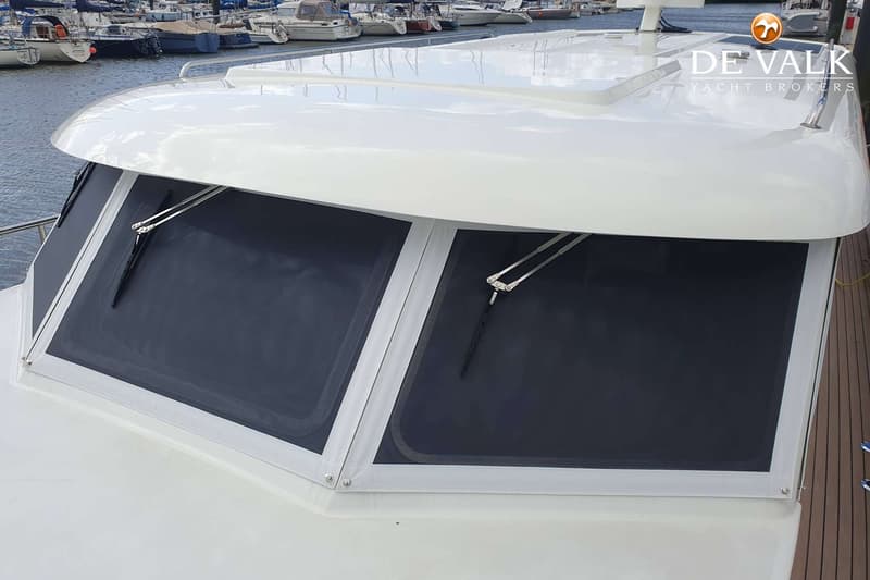 De voorruit van een boot is zichtbaar, bedekt met donkere zonwering en voorzien van twee ruitenwissers.