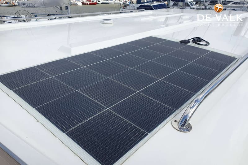 Een groot zonnepaneel is gemonteerd op het witte dek van een boot, met een roestvrijstalen handgreep ernaast.
