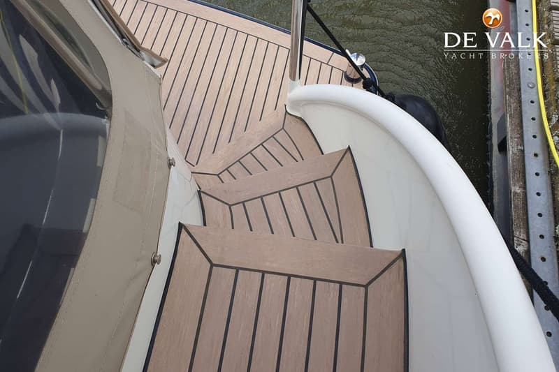 Een houten trap met vier treden en een metalen leuning leidt naar een dek met houten planken.