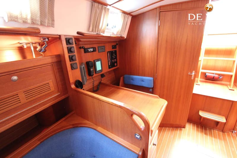Een houten interieur van een boot met een navigatiehoek, een blauwe zitting en een deur. — Victoire 42 Classic