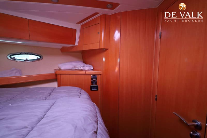 Een kajuit met een bed, houten kasten, een patrijspoort en een deur. — Beneteau Flyer 12 Cabin