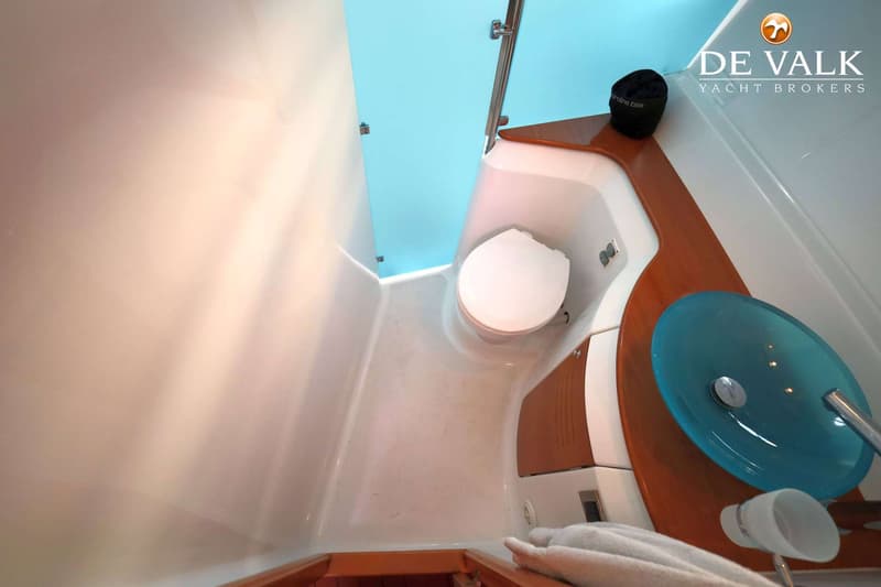 De foto toont een badkamer met een wit toilet, een blauwe wasbak en houten accenten.