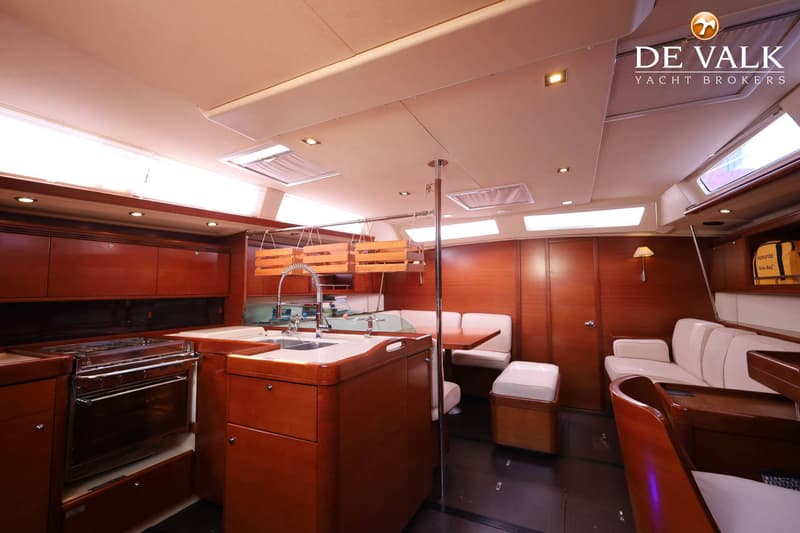 De foto toont het interieur van een boot met een kombuis, zithoek en houten afwerking. — Dufour 485 Grand Large