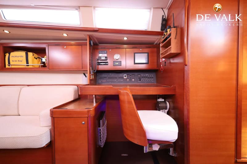 De foto toont een interieur van een boot met een navigatiehoek, een bank en houten afwerking. — Dufour 485 Grand Large