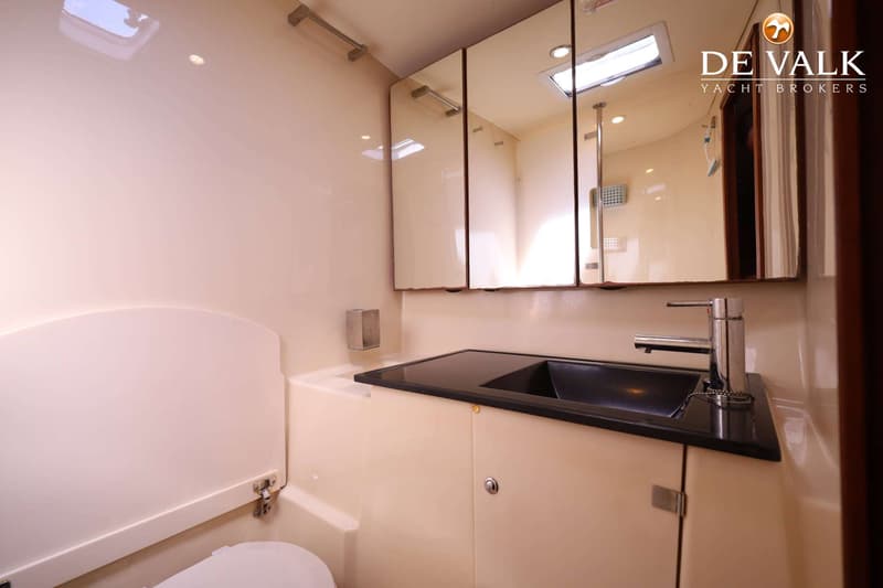 Een badkamer met een toilet, een wastafel met kraan, een spiegelkast en een dakluik.