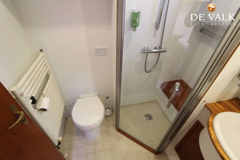 Een badkamer met een toilet, een douchecabine en een wastafel is zichtbaar.