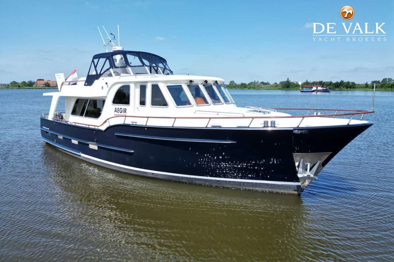 Een donkerblauwe motorboot met witte opbouw en de naam "AEGIR" op de zijkant ligt in het water. — Vripack Searocco 1500