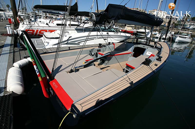 Een zeilboot met een teakdek en grijze kussens ligt afgemeerd in een jachthaven. — Saffier SE27 Leisure