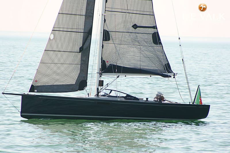 Een donkergrijze zeilboot met zwarte zeilen vaart op rustig water, met een vlag aan de achtersteven. — Saffier SE27 Leisure