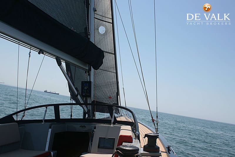 Een zeilboot vaart op open water met een zwart zeil en een vrachtschip in de verte. — Saffier SE27 Leisure
