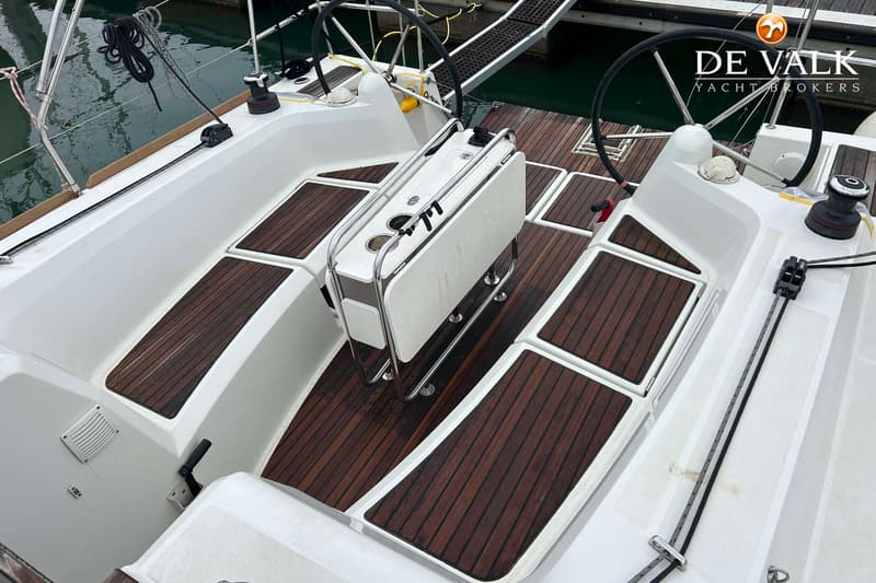 De kuip van een zeilboot met een houten dek, twee stuurwielen en een inklapbare tafel. — Jeanneau Sun Odyssey 349