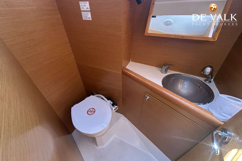 Een bootinterieur met een toilet, een wastafel met kraan en een spiegel.