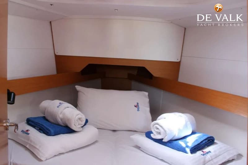 Een kajuit met een tweepersoonsbed, twee kussens en opgerolde handdoeken. — Jeanneau Sun Odyssey 349