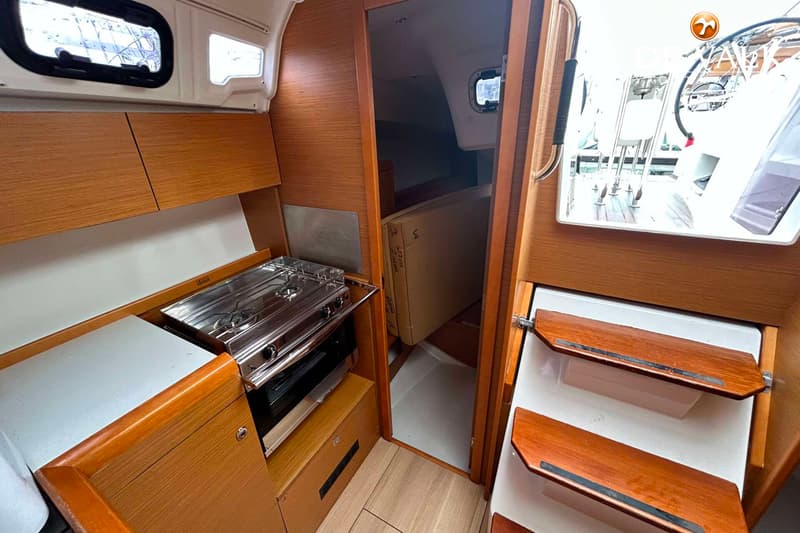 Een interieur van een boot met een kombuis aan de linkerkant, een doorgang naar een hut en een trap naar het dek.