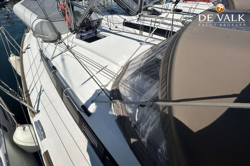 Een deel van het dek van een zeilboot met een grijze sprayhood en een opblaasbare bijboot. — Jeanneau Sun Odyssey 349