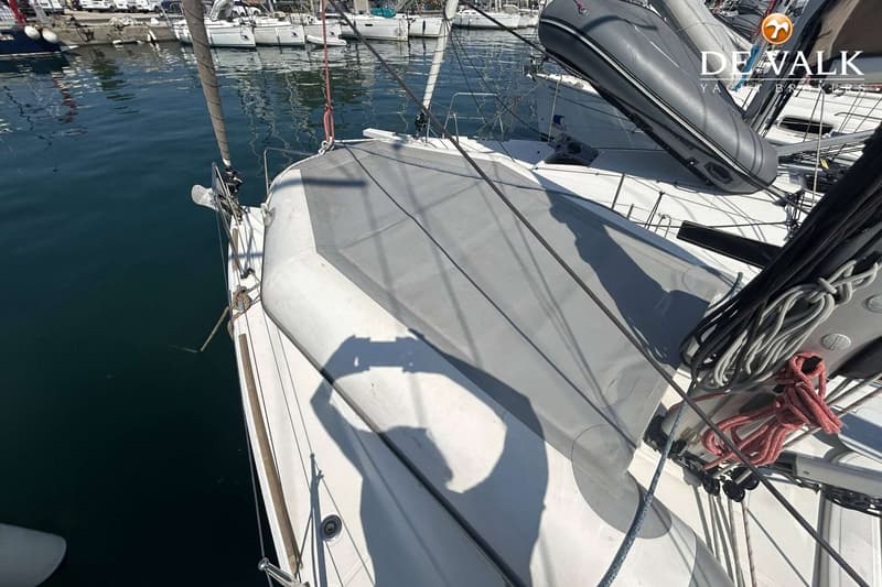 Een bovenaanzicht van een zeilboot in een haven, met een opblaasboot en zeilen op het dek. — Jeanneau Sun Odyssey 349