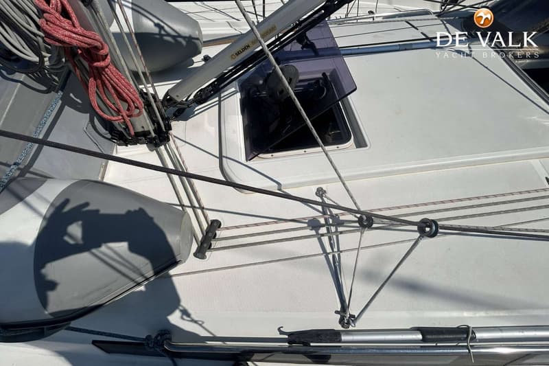 Een bovenaanzicht van een wit dek met touwen, stootwillen, een open luik en een mast met "SELDEN" erop.