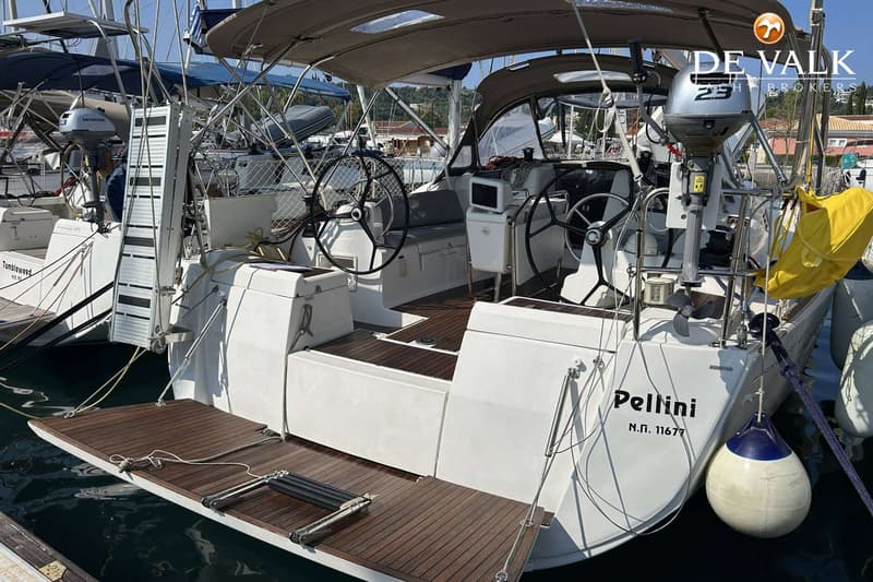 De achterzijde van een witte zeilboot met een teakhouten zwemplateau en twee stuurwielen is zichtbaar.