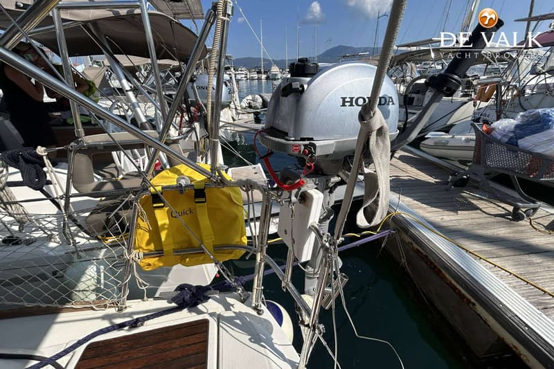 Een Honda buitenboordmotor hangt aan de achterkant van een boot, met een gele tas en een winkelwagentje op de steiger.