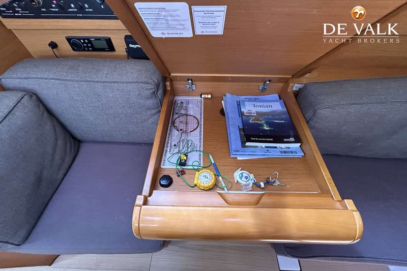 Een open klaptafel met nautische kaarten, een passer, een liniaal, een sleutelbos en een pen, geflankeerd door twee grijze…