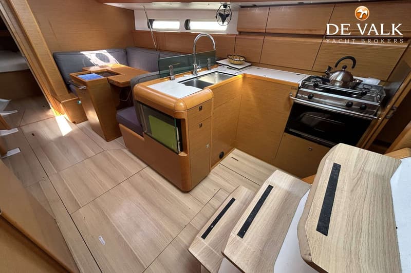 De foto toont een interieur van een boot met een kombuis, zithoek, houten vloer en trap. — Jeanneau Sun Odyssey 419