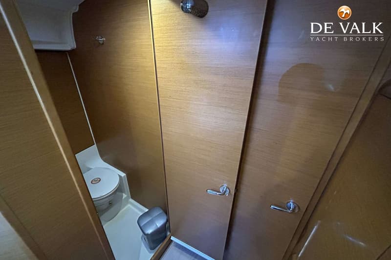 Een toiletruimte met een wit toilet, een grijze prullenbak en houten wanden en deuren.