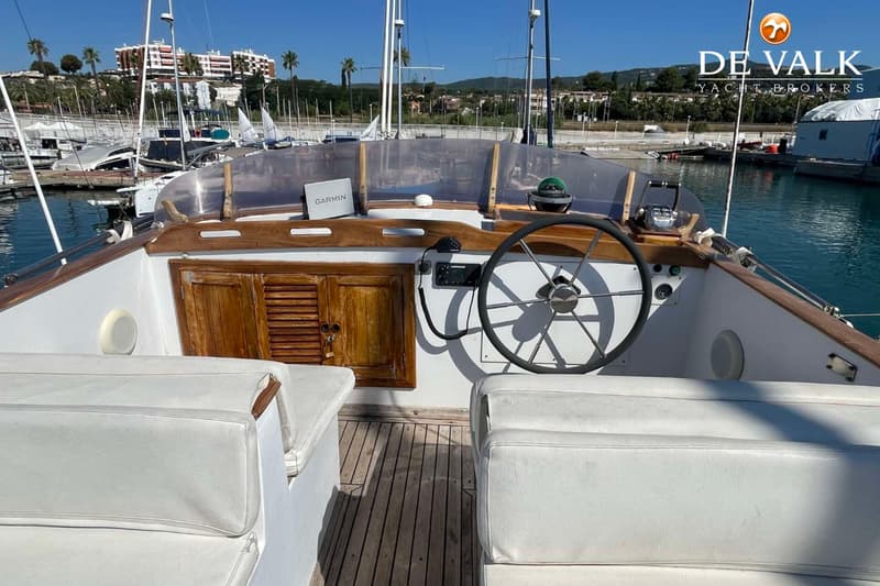 Een boot met een stuurwiel, navigatieapparatuur en witte kussens in een haven. — CHUNG HWA BOAT BUILDING TRAWLER 34