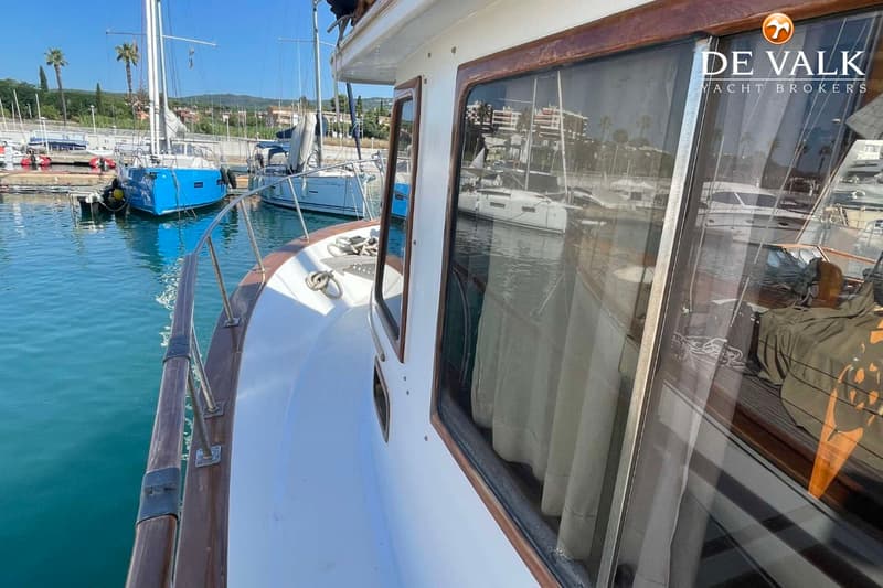 Een witte boot met houten details en ramen met gordijnen, liggend in een jachthaven. — CHUNG HWA BOAT BUILDING TRAWLER 34