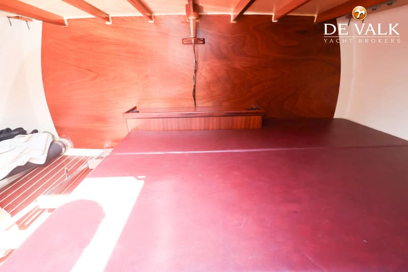 De foto toont een kajuit met een rood kussen, houten wanden en een houten plafond met balken. — Custom Aluminium Cruiser