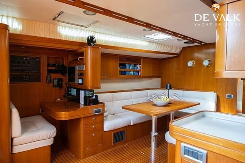 De foto toont een houten interieur van een boot met een zithoek, tafel, navigatiehoek en opbergkasten. — Baltic 60