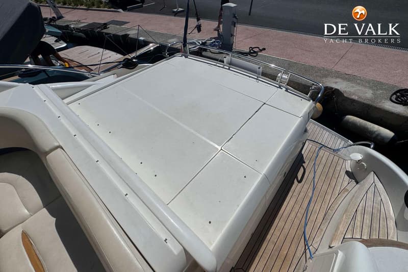 Een bovenaanzicht van het achterdek van een boot met een wit dek en een teakhouten vloer. — Princess V48