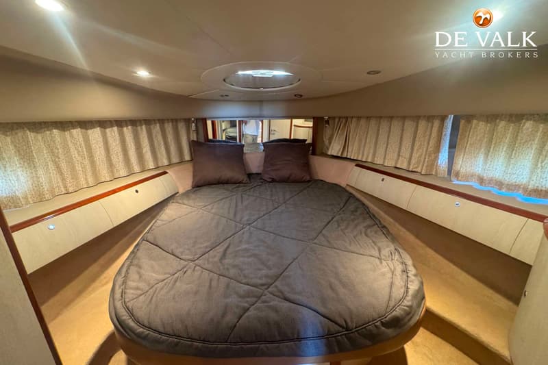 Een kajuit met een tweepersoonsbed, twee kussens, een dekbed, gordijnen en een patrijspoort in het plafond. — Princess V48