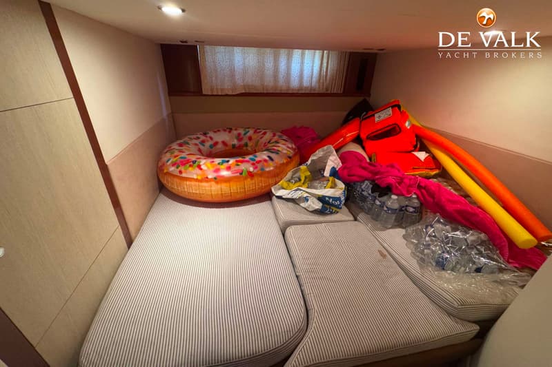 De foto toont een kajuit met gestreepte kussens, een opblaasbare donut, zwemvesten, zwemnoodels en waterflessen.