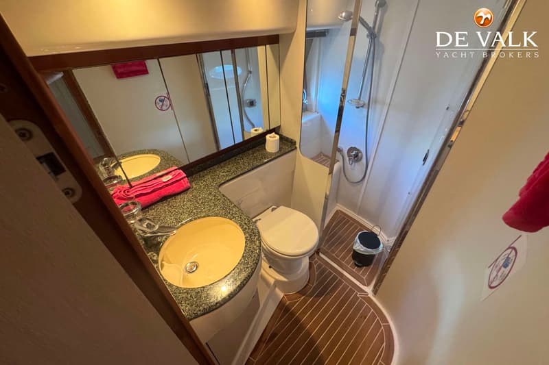 Een badkamer met een wastafel, toilet en douchecabine, met een spiegel boven de wastafel.
