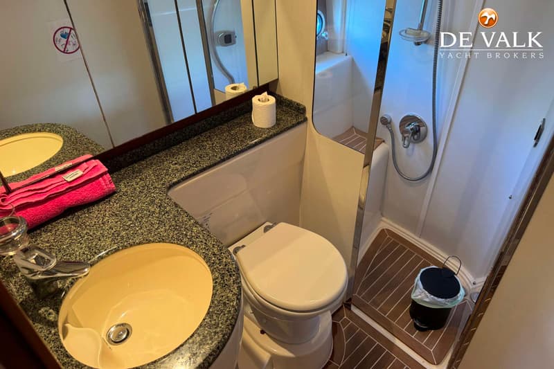 Een badkamer met een wastafel, toilet en douchecabine is zichtbaar.