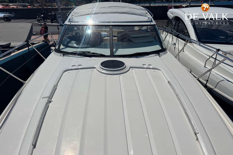 Een witte boot met een zwart luik op het voordek, omringd door relingen en een voorruit met twee ruitenwissers.