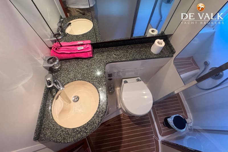 Een badkamer met twee wastafels, een toilet en een douchecabine is zichtbaar.