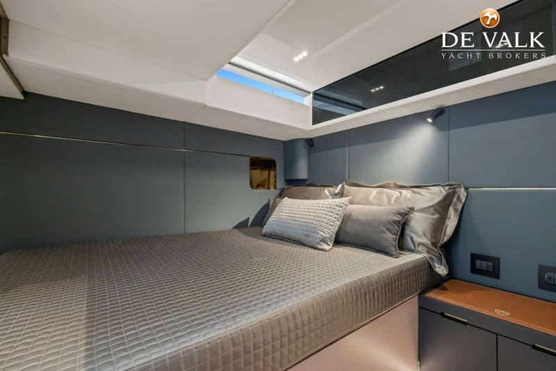 Een kajuit met een bed met grijze sprei en kussens, een raam en een patrijspoort. — Forte 47 GT