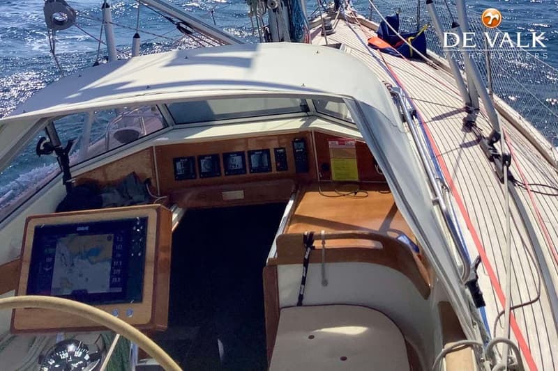Een bovenaanzicht van de cockpit van een zeilboot met een plotter, instrumenten en een houten dek. — Najad 391