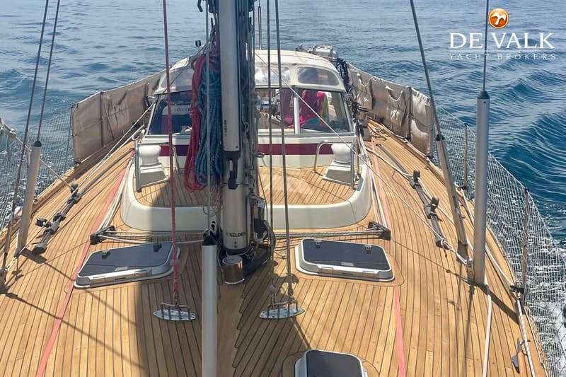 Een bovenaanzicht van het dek van een zeilboot met een houten dek, mast, touwen en een kajuit. — Najad 391