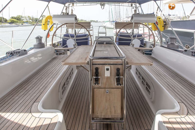 Een achterdek van een zeilboot met twee stuurwielen, een houten tafel en een teakhouten vloer. — Hanse 540e