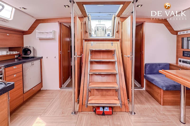 Een interieur van een boot met een kombuis, een trap naar het dek, een bank en een tafel. — Hanse 540e
