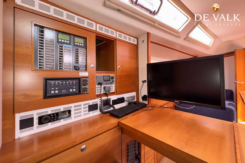 De foto toont een houten interieur van een boot met een navigatiepaneel, een Dell-monitor en een toetsenbord. — Hanse 540e