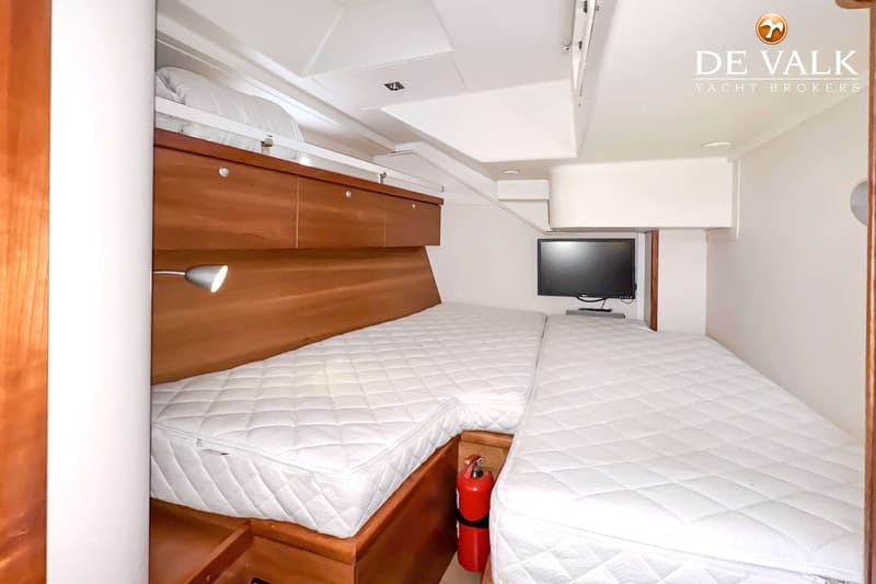 Een kajuit met twee bedden, een stapelbed, een televisie en een brandblusser. — Hanse 540e