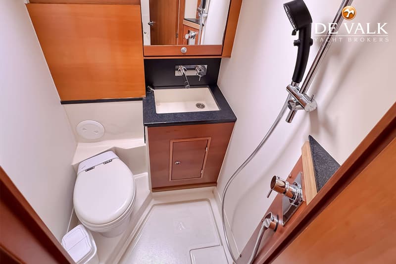 Een badkamer met een toilet, wastafel met spiegel en een douchekop aan de muur.