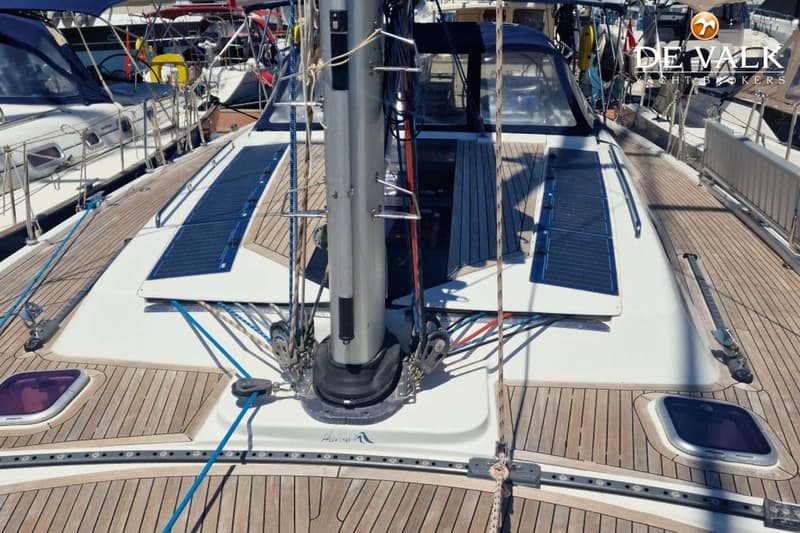 Een bovenaanzicht van het dek van een zeilboot met een mast, touwen, zonnepanelen en een houten dek. — Hanse 540e