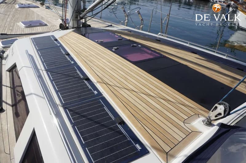 De foto toont een deel van het dek van een zeilboot met zonnepanelen, houten dekdelen en patrijspoorten. — Hanse 540e
