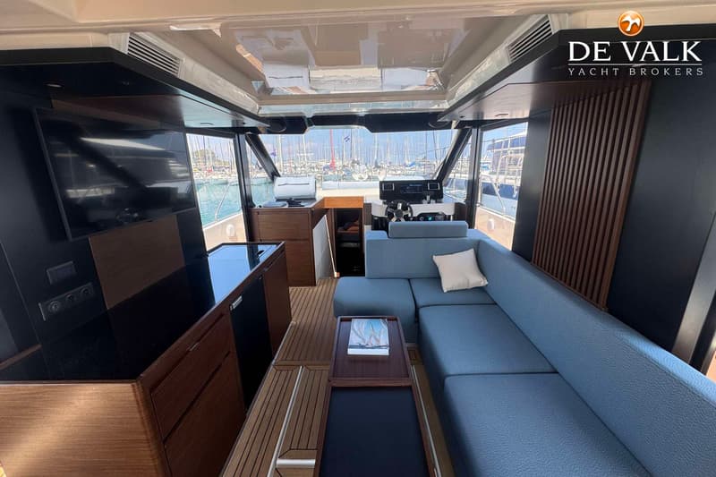 De foto toont het interieur van een boot met een blauwe bank, een stuurstand en uitzicht op een haven. — Wia 520 HT