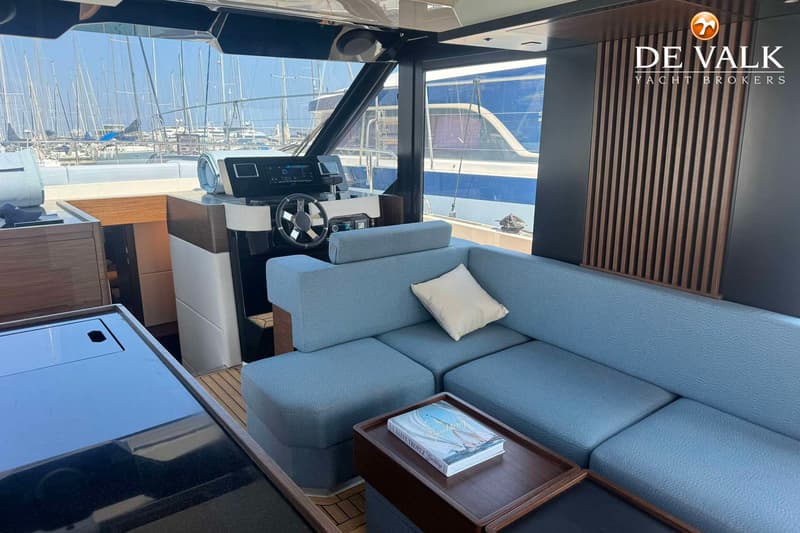 Een interieur van een boot met een stuurstand, een blauwe bank met kussens en een salontafel met een boek. — Wia 520 HT
